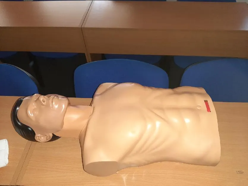 Figurína pro nácvik resuscitace položená na lavici v učebně